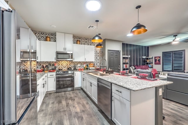 7472 Garnet Moon St, North Las Vegas, NV 89084 - kitchen featuring stainless steel appliances, open floor plan, white cabinets, light wood-type flooring, and a peninsula