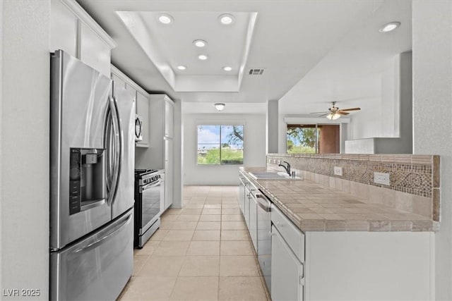 664 Peachy Canyon Cir Unit 103, Las Vegas, NV 89144 - kitchen with appliances with stainless steel finishes, a tray ceiling, white cabinets, recessed lighting, and ceiling fan