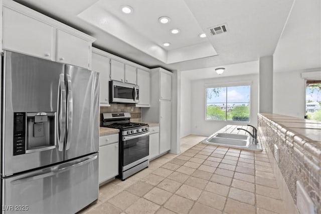 664 Peachy Canyon Cir Unit 103, Las Vegas, NV 89144 - kitchen with appliances with stainless steel finishes, backsplash, a raised ceiling, light countertops, and white cabinets