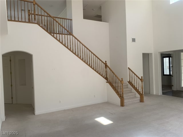 3328 White Bark Pine St, Las Vegas, NV 89129 - unfurnished living room featuring a towering ceiling, carpet floors, arched walkways, and stairway