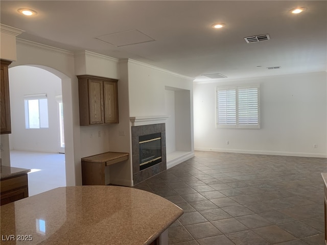 3328 White Bark Pine St, Las Vegas, NV 89129 - unfurnished living room with crown molding, arched walkways, a fireplace, stone tile floors, and recessed lighting