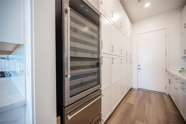 11248 Rebel Dome Ct, Las Vegas, NV 89141 - interior space with beverage cooler, light wood-style flooring, white cabinets, light stone countertops, and recessed lighting
