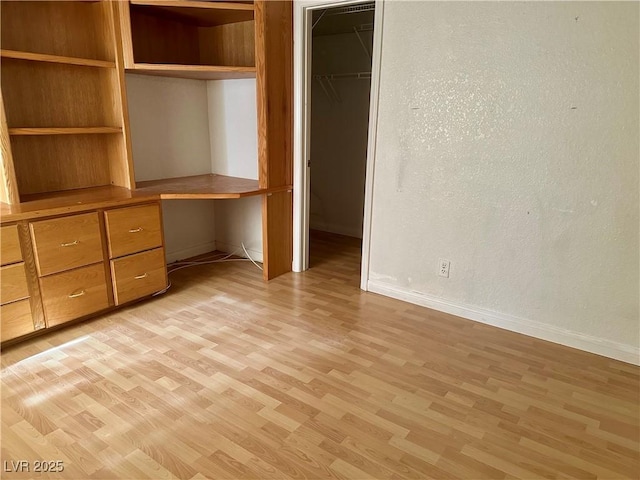 1409 Santa Margarita St Unit B, Las Vegas, NV 89146 - unfurnished bedroom with built in study area, light wood-style floors, a spacious closet, a closet, and a textured wall