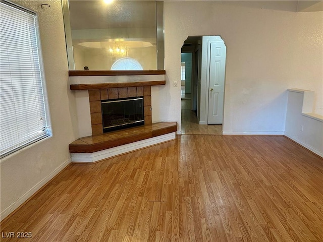 1409 Santa Margarita St Unit B, Las Vegas, NV 89146 - unfurnished living room featuring wood finished floors, a fireplace, and arched walkways