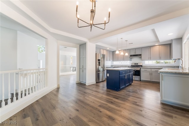 1403 Graystone Canyon Ave, Las Vegas, NV 89183 - kitchen featuring appliances with stainless steel finishes, a raised ceiling, under cabinet range hood, a center island, and a chandelier