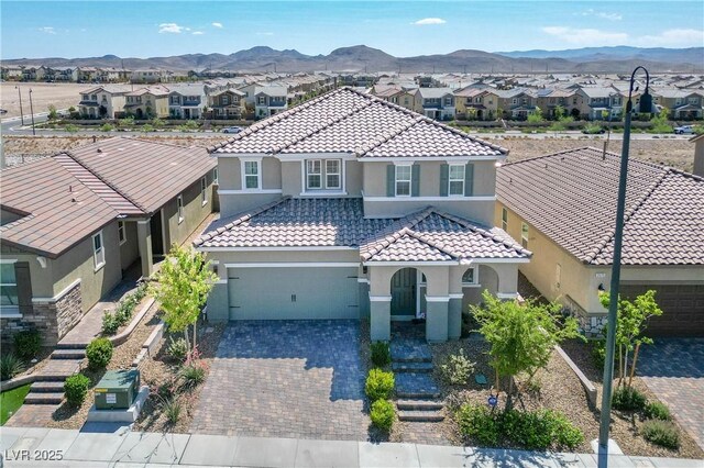 2577 Tolmezzo St, Henderson, NV 89044 - mediterranean / spanish house with a residential view, a tiled roof, an attached garage, stucco siding, and a mountain view