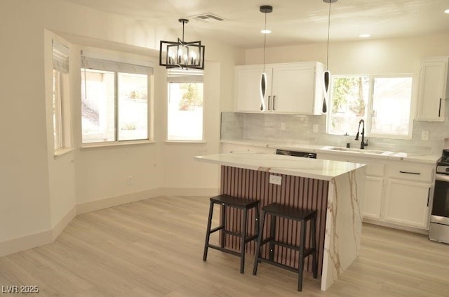 7253 Alsop Ct, Las Vegas, NV 89156 - kitchen with white cabinets, a breakfast bar, backsplash, and a center island