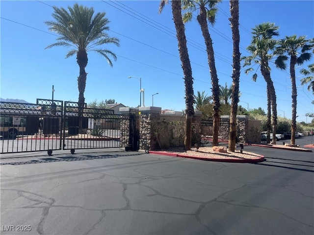 1830 N Buffalo Dr Unit 2021, Las Vegas, NV 89128 - view of asphalt road featuring a gate, curbs, street lighting, and a gated entry