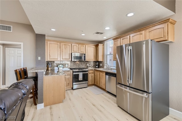63 E Agate Ave Unit 509, Las Vegas, NV 89123 - kitchen with stainless steel appliances, light brown cabinets, a peninsula, light wood-style floors, and recessed lighting