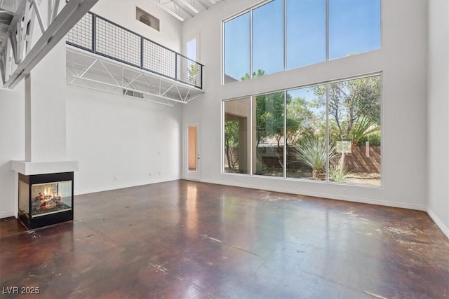 5603 Deer Creek Falls Ct, Las Vegas, NV 89118 - unfurnished living room featuring a high ceiling, finished concrete floors, and a multi sided fireplace