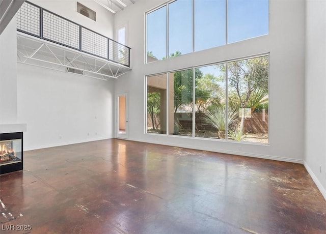 5603 Deer Creek Falls Ct, Las Vegas, NV 89118 - unfurnished living room with a high ceiling, finished concrete floors, and a multi sided fireplace