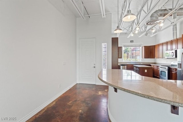 5603 Deer Creek Falls Ct, Las Vegas, NV 89118 - kitchen featuring stainless steel appliances, finished concrete floors, light stone countertops, a breakfast bar area, and a towering ceiling