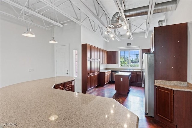 5603 Deer Creek Falls Ct, Las Vegas, NV 89118 - kitchen featuring stainless steel appliances, a kitchen island, hanging light fixtures, a towering ceiling, and light stone countertops