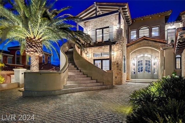 30 Via Tiberius Way, Henderson, NV 89011 - exterior entry at night with a balcony, stone siding, and stucco siding