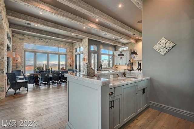30 Via Tiberius Way, Henderson, NV 89011 - kitchen featuring beam ceiling, wood-type flooring, light stone countertops, a peninsula, and gray cabinets