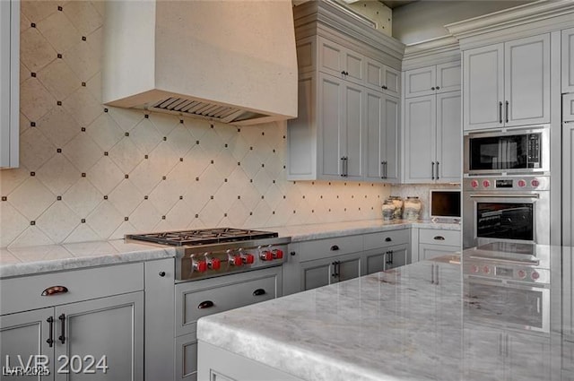 30 Via Tiberius Way, Henderson, NV 89011 - kitchen with stainless steel appliances, premium range hood, light stone counters, and backsplash