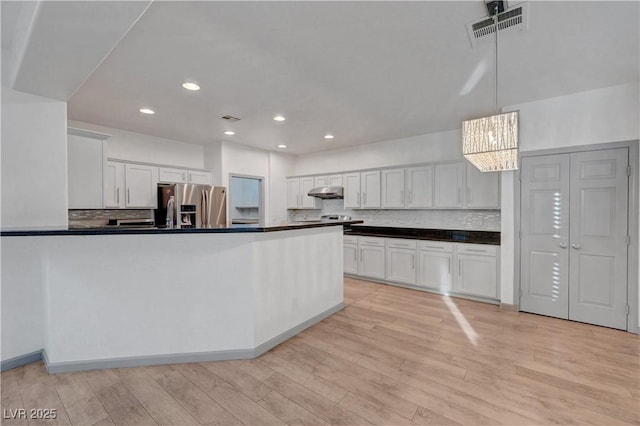 1069 Aspen Cliff Dr, Henderson, NV 89011 - kitchen with stainless steel fridge with ice dispenser, dark countertops, a chandelier, light wood-style floors, and recessed lighting