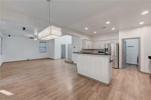 1069 Aspen Cliff Dr, Henderson, NV 89011 - kitchen with stainless steel fridge with ice dispenser, dark countertops, open floor plan, recessed lighting, and a peninsula