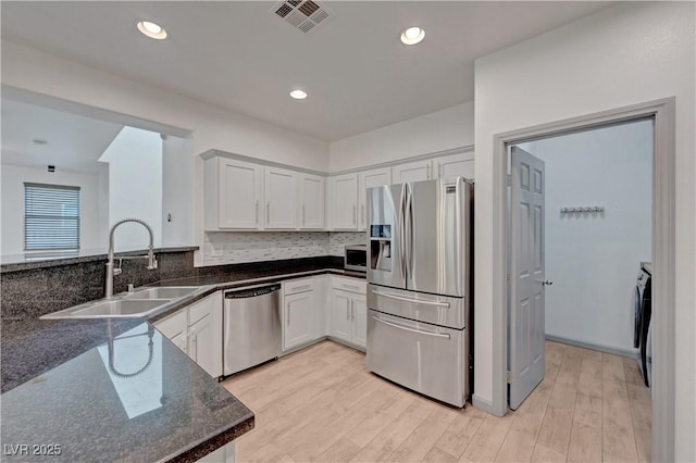 1069 Aspen Cliff Dr, Henderson, NV 89011 - kitchen featuring appliances with stainless steel finishes, light wood finished floors, white cabinetry, dark stone counters, and recessed lighting
