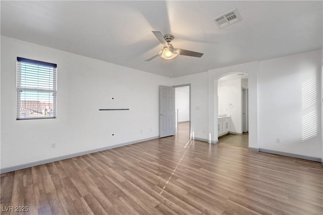 1069 Aspen Cliff Dr, Henderson, NV 89011 - unfurnished bedroom featuring arched walkways, light wood finished floors, ensuite bathroom, and ceiling fan