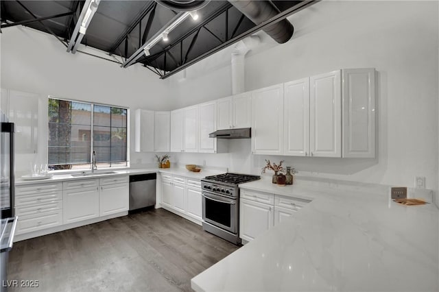 5015 Thunder River Cir, Las Vegas, NV 89148 - kitchen featuring appliances with stainless steel finishes, under cabinet range hood, a high ceiling, white cabinetry, and dark wood finished floors