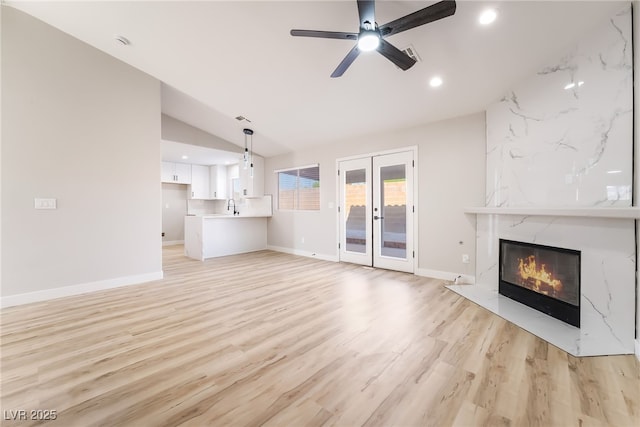 5417 Bible Cir, North Las Vegas, NV 89031 - unfurnished living room with vaulted ceiling, french doors, light wood-style floors, ceiling fan, and a fireplace