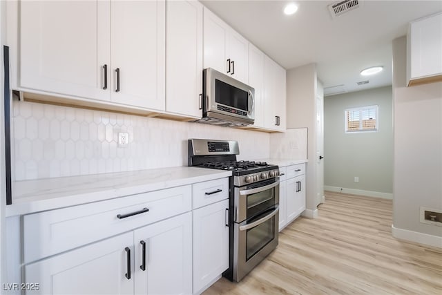 5417 Bible Cir, North Las Vegas, NV 89031 - kitchen with stainless steel appliances, light stone counters, white cabinetry, light wood finished floors, and tasteful backsplash