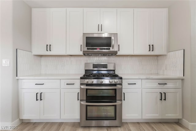 5417 Bible Cir, North Las Vegas, NV 89031 - kitchen featuring appliances with stainless steel finishes, white cabinetry, backsplash, and light wood-style floors