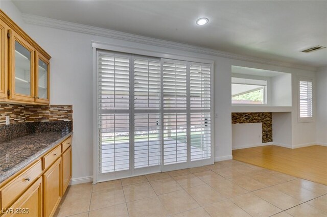 10513 Shanna Trellis Ave, Las Vegas, NV 89144 - kitchen with ornamental molding, backsplash, glass insert cabinets, light tile patterned floors, and dark stone countertops
