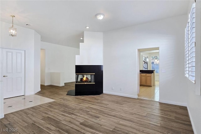 8981 Rivers Edge Dr, Las Vegas, NV 89117 - unfurnished living room featuring light wood-style floors, recessed lighting, a chandelier, and a multi sided fireplace