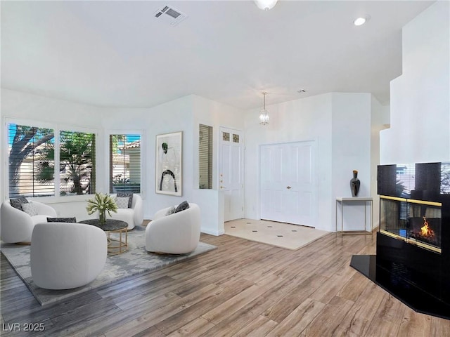 8981 Rivers Edge Dr, Las Vegas, NV 89117 - living area featuring wood finished floors, a chandelier, and a glass covered fireplace