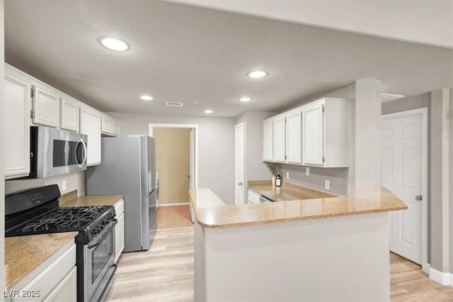 9975 Peace Way Unit 2009, Las Vegas, NV 89147 - kitchen featuring appliances with stainless steel finishes, light wood-style floors, recessed lighting, white cabinetry, and a peninsula