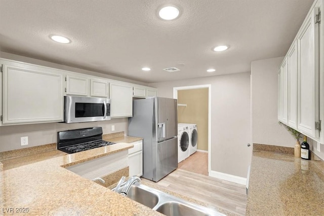 9975 Peace Way Unit 2009, Las Vegas, NV 89147 - kitchen with washer and clothes dryer, appliances with stainless steel finishes, white cabinets, light countertops, and a textured ceiling