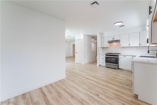 1808 E Saint Louis Ave, Las Vegas, NV 89104 - kitchen with stainless steel stove, light wood-type flooring, decorative backsplash, light countertops, and white cabinets