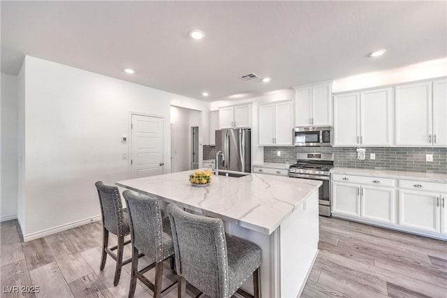 3821 Nesting Wren Dr, North Las Vegas, NV 89084 - kitchen featuring stainless steel appliances, a center island with sink, tasteful backsplash, white cabinets, and recessed lighting