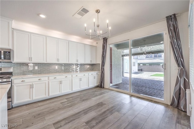 3821 Nesting Wren Dr, North Las Vegas, NV 89084 - kitchen featuring appliances with stainless steel finishes, a chandelier, light wood-style floors, light countertops, and white cabinets