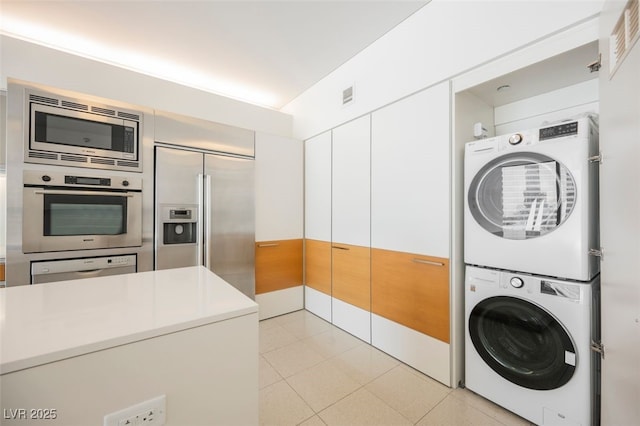3726 Las Vegas Blvd Unit 704, Las Vegas, NV 89158 - kitchen featuring built in appliances, stacked washing machine and dryer, light countertops, white cabinetry, and light tile patterned floors
