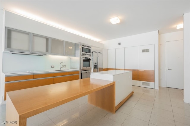 3726 Las Vegas Blvd Unit 704, Las Vegas, NV 89158 - kitchen with appliances with stainless steel finishes, a kitchen island, light countertops, a warming drawer, and glass insert cabinets