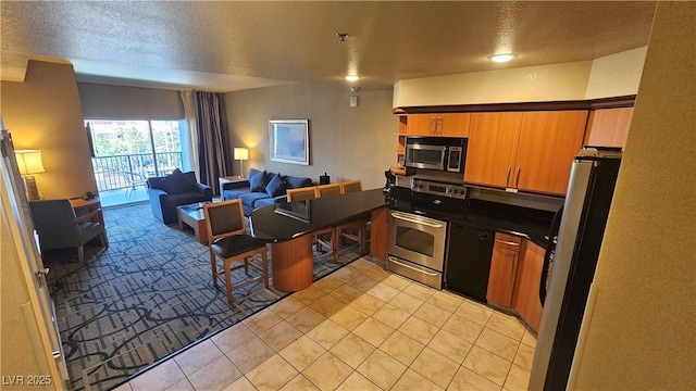 211 E Flamingo Rd Unit 405, Las Vegas, NV 89169 - kitchen with stainless steel appliances, open floor plan, dark countertops, light tile patterned flooring, and a peninsula