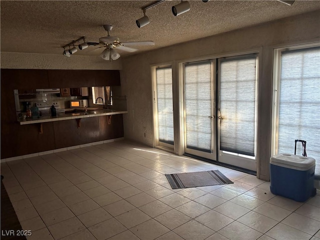 4928 E Philadelphia Ave, Las Vegas, NV 89104 - kitchen featuring a textured ceiling, light tile patterned flooring, a ceiling fan, a kitchen breakfast bar, and track lighting