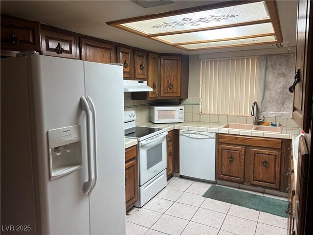 4928 E Philadelphia Ave, Las Vegas, NV 89104 - kitchen featuring white appliances, under cabinet range hood, light tile patterned floors, backsplash, and tile counters