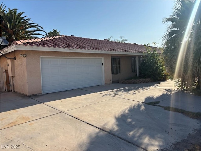4928 E Philadelphia Ave, Las Vegas, NV 89104 - view of front of house featuring stucco siding, driveway, a tile roof, and a garage