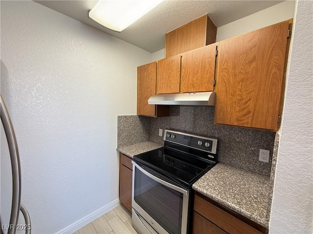 3606 Di Salvo Dr Unit 133, Las Vegas, NV 89103 - kitchen with stainless steel range with electric stovetop, under cabinet range hood, backsplash, a textured wall, and brown cabinetry