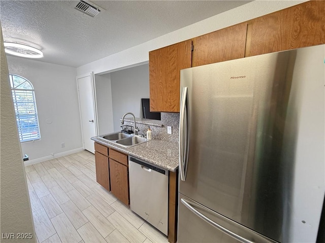 3606 Di Salvo Dr Unit 133, Las Vegas, NV 89103 - kitchen featuring stainless steel appliances, a textured ceiling, brown cabinets, light countertops, and decorative backsplash