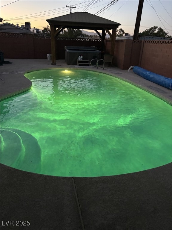 704 N Wallace Dr, Las Vegas, NV 89107 - pool at dusk with a fenced backyard, a gazebo, a patio, and a hot tub