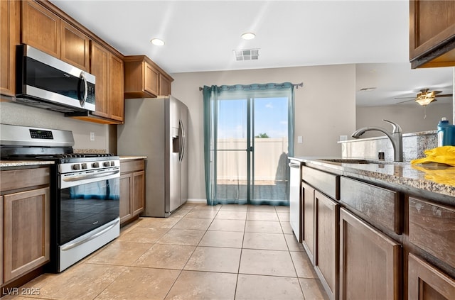 2175 Limestone Cove Ct, Laughlin, NV 89029 - kitchen featuring appliances with stainless steel finishes, a ceiling fan, light stone counters, brown cabinetry, and recessed lighting