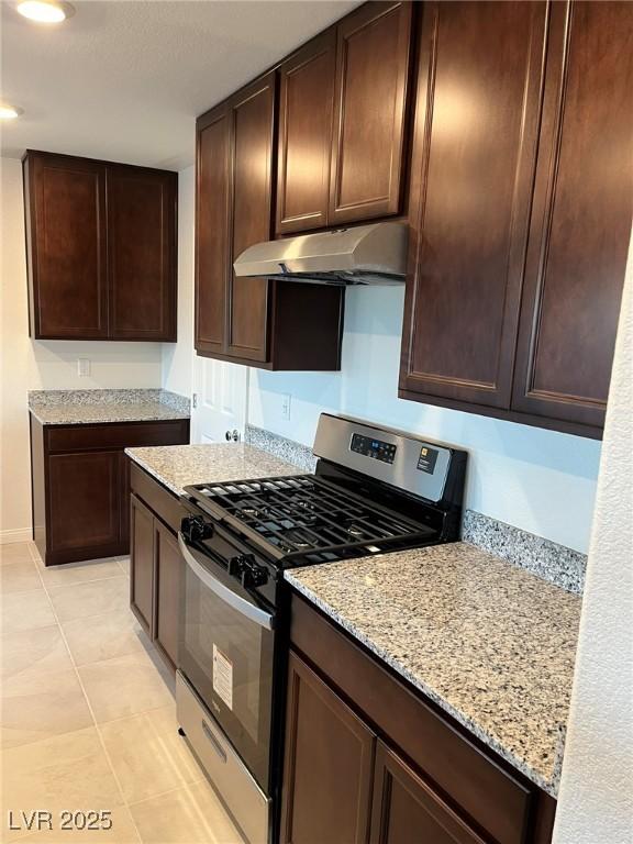 4056 Campeche Ave, Las Vegas, NV 89121 - kitchen featuring gas stove, under cabinet range hood, light stone countertops, dark brown cabinets, and light tile patterned floors