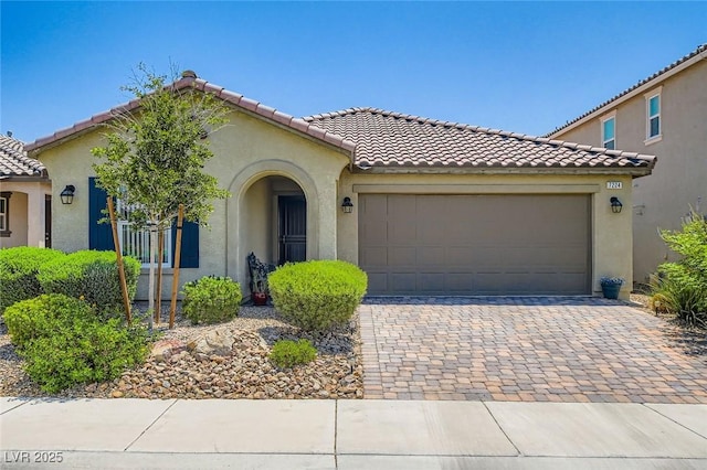 7224 Piute Mesa St, North Las Vegas, NV 89084 - mediterranean / spanish-style house featuring stucco siding, an attached garage, decorative driveway, and a tile roof
