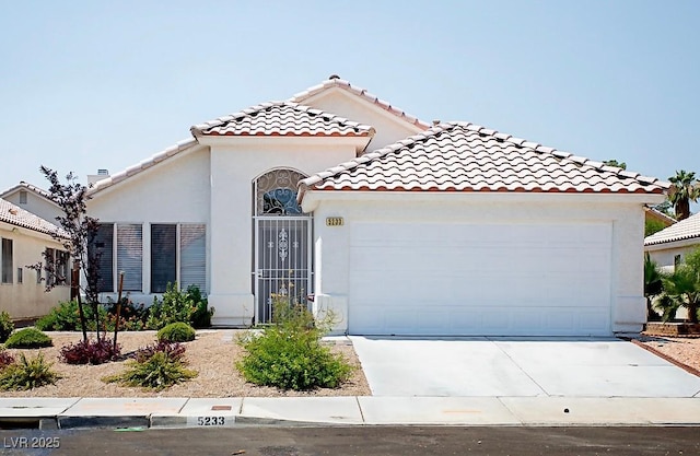5233 Camino Del Rancho, Las Vegas, NV 89130 - mediterranean / spanish home featuring a garage, driveway, stucco siding, and a tile roof