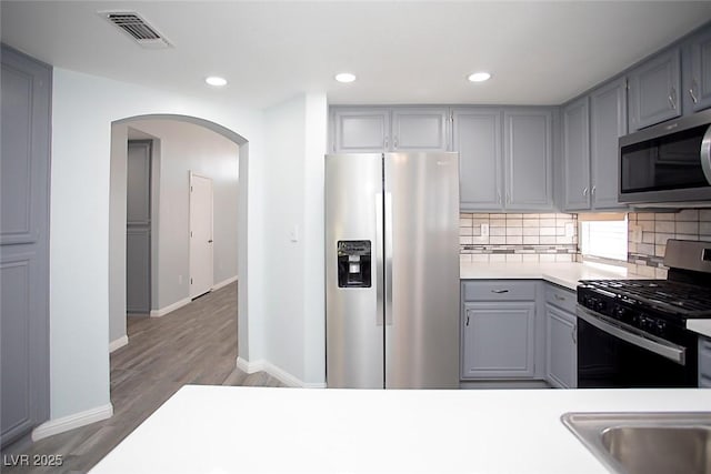 5233 Camino Del Rancho, Las Vegas, NV 89130 - kitchen with appliances with stainless steel finishes, gray cabinets, arched walkways, light countertops, and tasteful backsplash